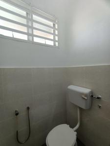 a bathroom with a white toilet and a window at KLIA Guesthouse-3 bedroom 2 bathroom in Banting