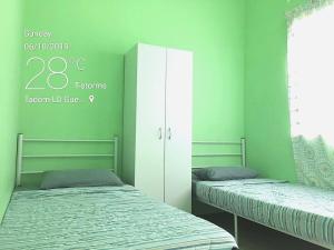 two beds in a room with green walls at KLIA Guesthouse-3 bedroom 2 bathroom in Banting