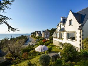 a house with an umbrella on a hill next to the ocean at Seaside Comfort in Erquy in Erquy
