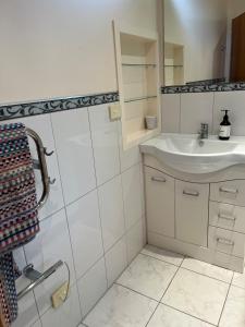 une salle de bain blanche avec un lavabo et un miroir dans l'établissement The Cottage on Hurford - New Plymouth, à New Plymouth 10 autres photos