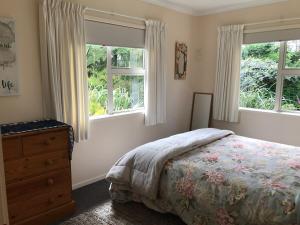 - une chambre avec un lit, une commode et 2 fenêtres dans l'établissement The Cottage on Hurford - New Plymouth, à New Plymouth