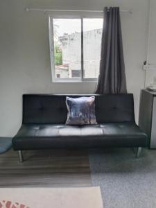 a black couch in a room with a window at Green Salad Hostel in Ban Thong Phlu