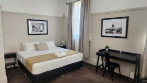 HamiltonにあるIslington Barracks Hotelのベッドと机とベッドのある寝室 sidx sidx sidx