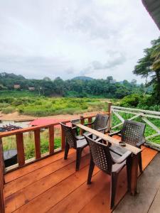 a wooden deck with chairs and a table on it at Wild Lodge Taman Negara in Kuala Tahan