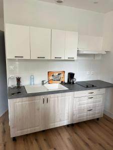 a kitchen with white cabinets and a sink at T2 Cosy, agréable fonctionnel et douillet, 1 lit 140 et un BZ , Wifi gratuit, boîte à clés, proche commerces et gare routière, linge de lit et toilette offerts à partir de 4 nuits in Graulhet +11 photos