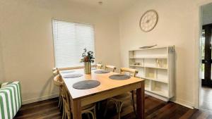 a dining room table with chairs and a clock on the wall at Teke Cottage in Wooli