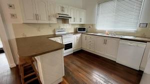 a kitchen with white cabinets and white appliances at Teke Cottage in Wooli
