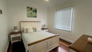 a bedroom with a white bed with two night stands and a window at Teke Cottage in Wooli +9 photos