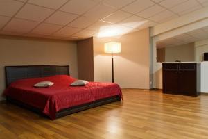 ウラジオストクにあるホテル リアルのベッドルーム1室(赤いベッドカバー、ランプ付)