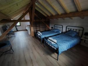 two beds in a attic room with wooden floors at Le bain nordique du lynx boréal in Entre-Deux-Monts