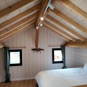 Un dormitorio con dos camas y dos ventanas. en Le bain nordique du lynx boréal, en Entre-Deux-Monts