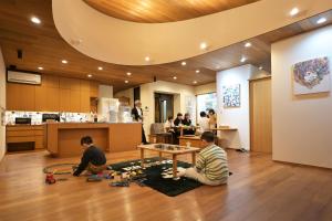 two men sitting on the floor in a room with a table at 隠れ家アートヴィラ Villa Revolla in Makinohara