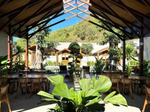 a restaurant with tables and chairs with a mountain in the background at Batatu Resort - Adults Only in Kuta Lombok