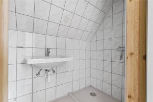 a white tiled bathroom with a sink and a shower at 6784-Allinge-Nordre-Strandvej-127 in Allinge