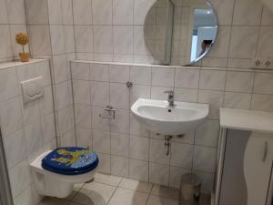 un bagno con lavandino, WC e specchio di Tuvalu a Remagen