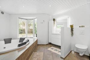 ein weißes Badezimmer mit Badewanne und Toilette in der Unterkunft 1584 Aakirkeby - Poseregårdsvejen 16 in Vester Sømarken + 16 Fotos