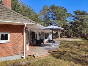 eine Holzterrasse mit einem Regenschirm auf einem Haus in der Unterkunft 1584 Aakirkeby - Poseregårdsvejen 16 in Vester Sømarken