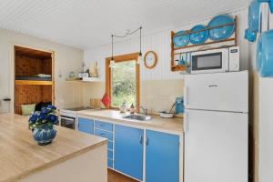 a kitchen with blue cabinets and a white refrigerator at 2700-Nexo-Munkegardsskoven-3 in Neksø +11 photos