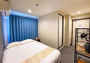 a bedroom with a bed and a blue curtain at Stay SAKURA Kyoto Station Shichijo in Kyoto