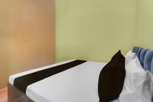 a white bed with a black pillow on it at Hotel O Tejaswi Hotel in Prayagraj