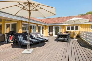 a wooden deck with chairs and an umbrella at 1563-Aakirkeby-Strandparken-8 in Vester Sømarken