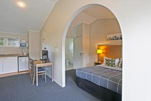 a hotel room with a bed and a table and a kitchen at Walton Park Motor Lodge in Warkworth