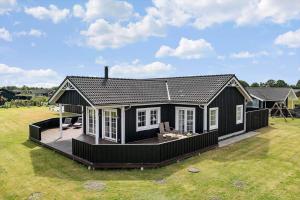 ein schwarzes Haus mit einer Terrasse in einem Hof in der Unterkunft OH362 Storvorde - Kongeørnen 74 in Storvorde