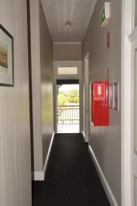 a hallway with a red door and a red suitcase at Royal Gatton Hotel in Gatton