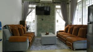 a living room with two couches and a tv at Diyar Villas Puncak M6-11 in Puncak