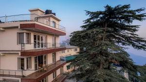 a building with a pine tree in front of it at SaffronStays Library Enclave Maharajah Suite - 1-BHK Luxury Apt with Valley View, Mall Road Mussoorie in Mussoorie