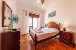 a bedroom with a bed and a dresser and a window at Bairro Apartment in Lagos in Lagos