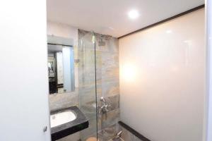 ein Badezimmer mit Waschbecken und Glasdusche in der Unterkunft Hotel Manila in Ahmedabad