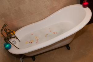 El baño incluye una bañera blanca con elementos decorativos. en Conacul Dascalu, en Trăisteni