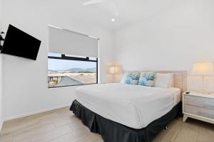 凯恩斯Mountain Air and Modern Flair 'Your Cairns Getaway'的一间带大床和窗户的白色卧室 更多37张照片