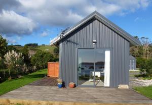 a small metal building with a large glass door at Oystercatcher Bay Boathouse in Coromandel Town