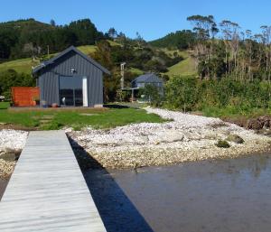 a wooden walkway leading to a house on a river at Oystercatcher Bay Boathouse in Coromandel Town