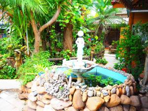a garden with a pool of water and plants at Three J Guesthouse in Kamphaeng Phet