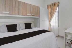 a bedroom with a large white bed and a window at OYO 94758 Kamila House in Pekanbaru