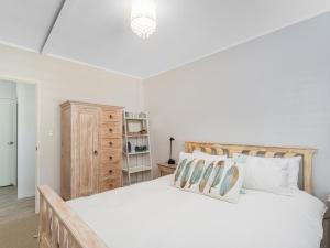 una camera da letto con un grande letto bianco con cuscini di Beverley Beach - Whangamata Holiday Home a Whangamata