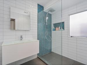 un bagno con doccia, lavandino e specchio di Beverley Beach - Whangamata Holiday Home a Whangamata Altre 27 foto
