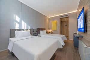 two beds in a hotel room with a flat screen tv at 汉庭优佳上海世博上南路店 in Shanghai