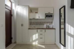 a white kitchen with white cabinets and a microwave at Centru Vechi Brasov in Braşov