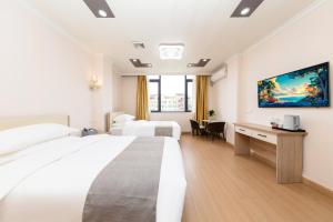 ein Hotelzimmer mit zwei Betten und einem Schreibtisch in der Unterkunft Shiyi Business Hotel Pazhou-Free shuttle bus for canton fair in Guangzhou + 40 Fotos