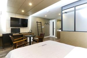 釜山にあるルイス ホテルのベッド、デスク、テレビが備わる客室です。