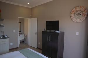 a bedroom with a bed and a clock on the wall at Andela Guesthouse in Bloemfontein