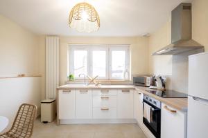 a kitchen with white cabinets and a sink and a window at L'Escapade Secrète balnéo - sauna - love room in Arras