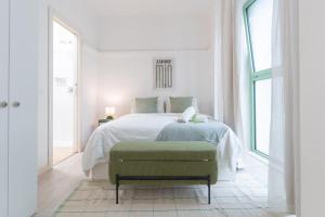 Un dormitorio blanco con una cama y una otomana verde. en DUOMO Wonderful Apartment for 6, en Milán