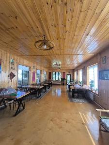 a large room with wooden ceilings and tables and windows at Ular Guest House in Kaindy