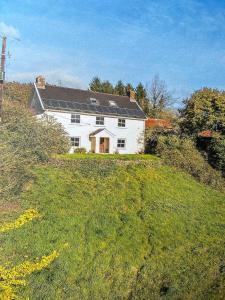 a white house on top of a grassy hill at Beautiful farmhouse on a hill in Sandford