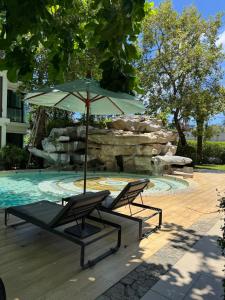 Dos sillas y una sombrilla junto a una piscina. en Pool Access Beachfront Studio, en Phuket